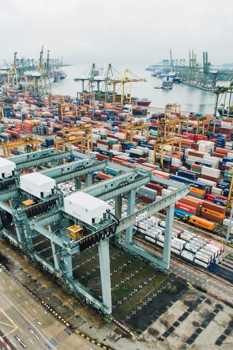 Puerto de contenedores visto desde el aire, con grúas pórtico y contenedores apilados junto al muelle