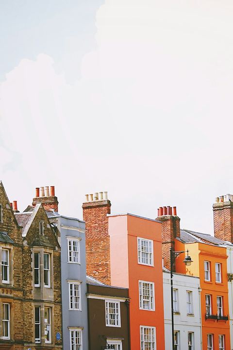 Hilera de casas urbanas de distintos colores con sus chimeneas de ladrillo